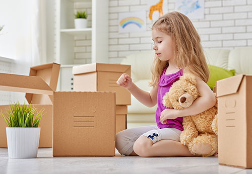 Child relocation law: Girl with teddy bear surrounded by moving boxes during a move
